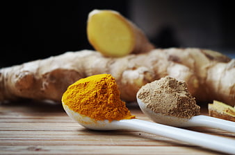 Turmeric and Ginger Powder on Spoons with Fresh Roots