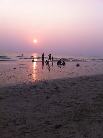 Silhouettes of People on Beach at Sunset with Pink Sky