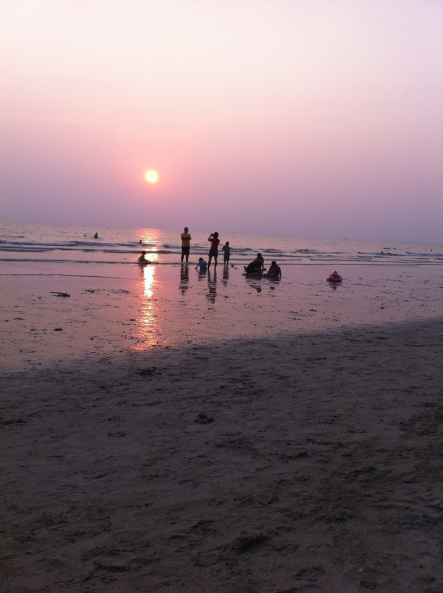 Silhouettes of People on Beach at Sunset with Pink Sky