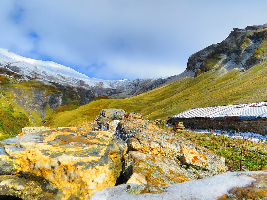 Alpine mountain landscape with rustic stone hut and snow