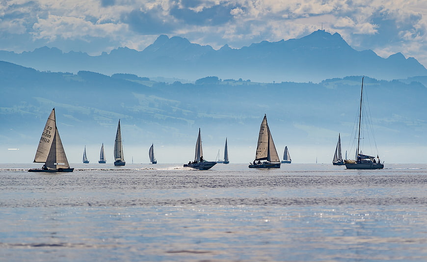 Sailboats Racing On Lake Constance With Mountain Backdrop