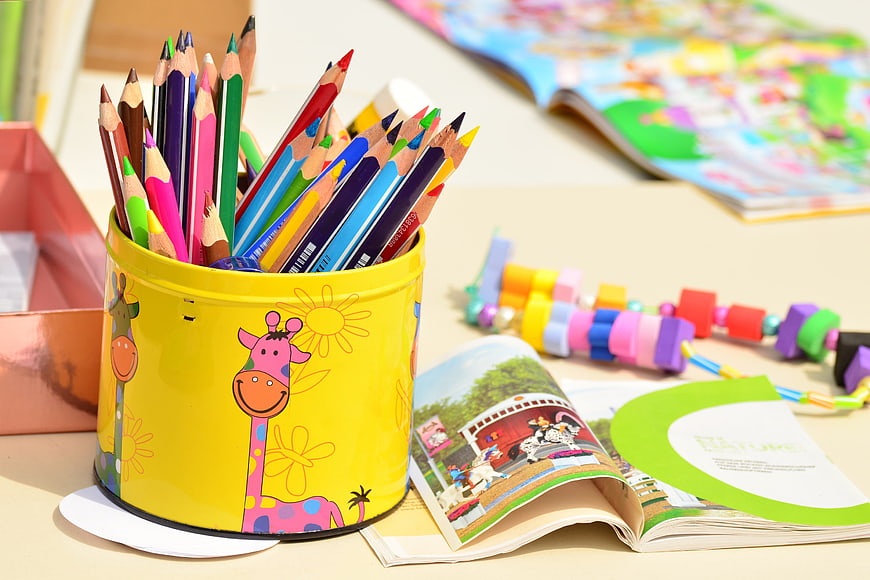 Colorful pencils in yellow tin with children's books and toys