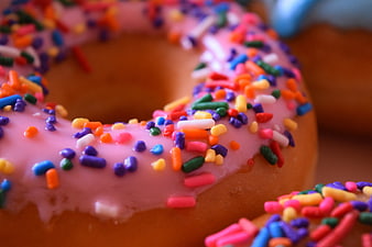 Close-up of pink frosted donut with colorful sprinkles