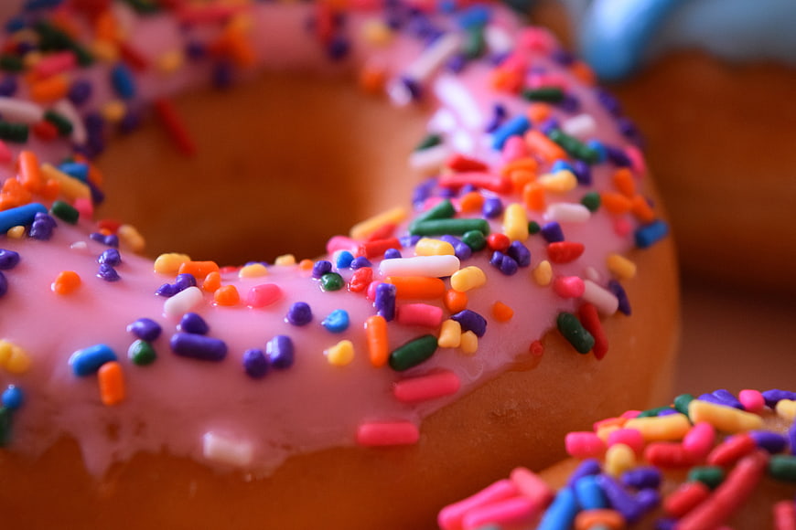 Close-up of pink frosted donut with colorful sprinkles