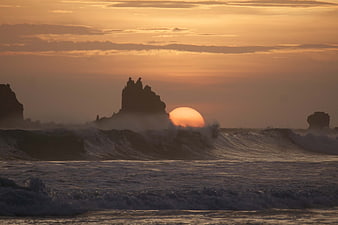 Dramatic Sunset Over Ocean Waves and Silhouetted Sea Stacks