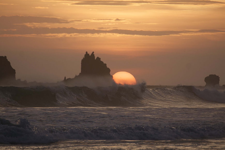 Dramatic Sunset Over Ocean Waves and Silhouetted Sea Stacks