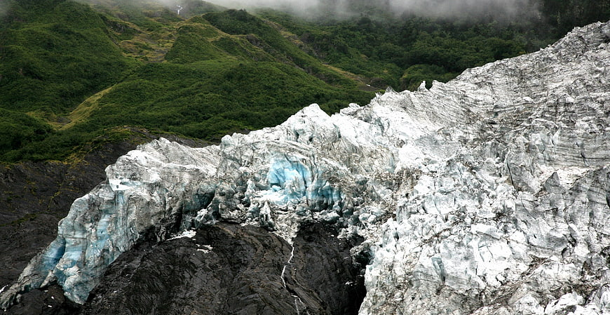 Majestic Glacier with Blue Ice and Green Mountain Background