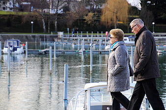 Senior couple walking together along a calm lake marina