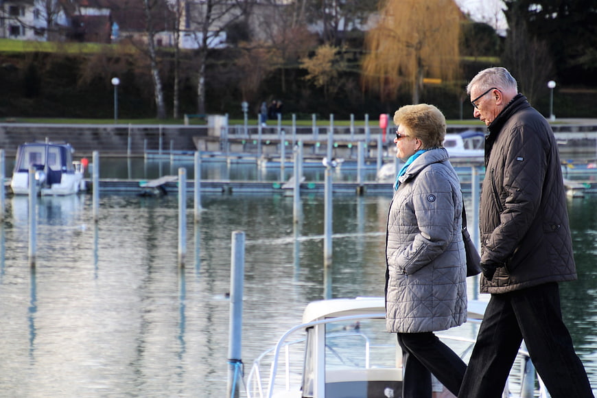 Senior couple walking together along a calm lake marina