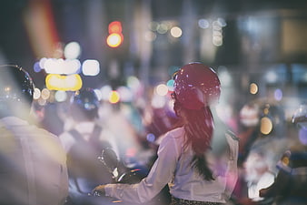 Woman on Scooter in Night Traffic with Bokeh Lights