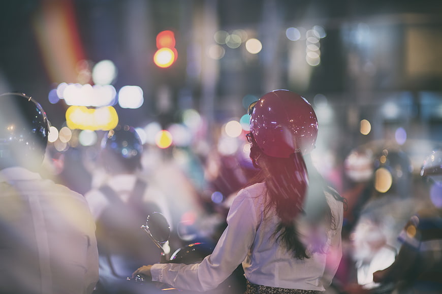 Woman on Scooter in Night Traffic with Bokeh Lights