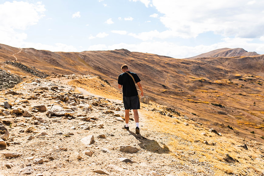 Man hiking on rocky mountain trail in autumn