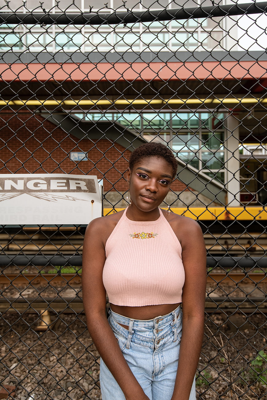 Young Black Woman Portrait in Front of Chain Link Fence