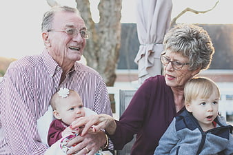 Senior grandparents holding baby and toddler outdoors