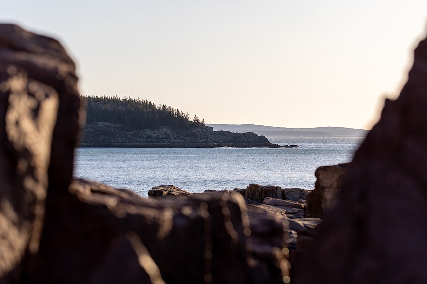 Scenic coastal view through rocky foreground with ocean and forested island