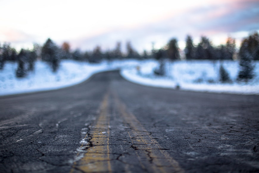Low angle view of cracked asphalt road in winter landscape