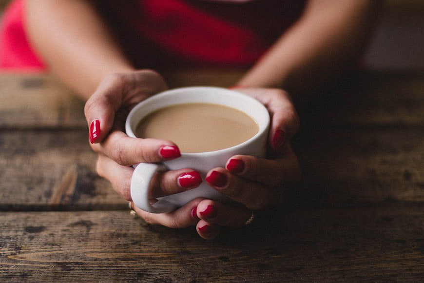Woman's Hands Holding White Coffee Cup on Wooden Table
