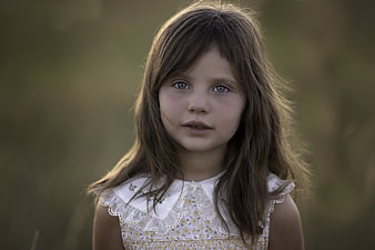 Portrait of a young girl with brown hair in a white dress