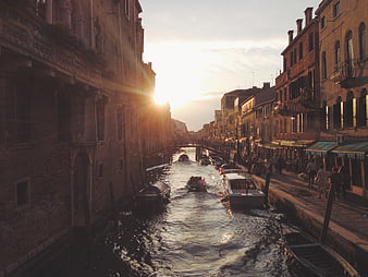 Sunset over a Venetian canal with boats and historic architecture