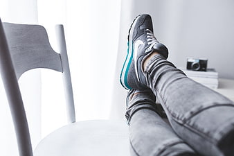 Relaxed Woman In Grey Nike Sneakers And Jeans Resting Legs