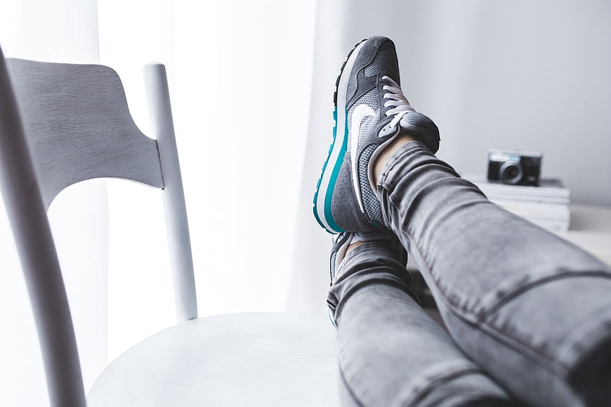 Relaxed Woman In Grey Nike Sneakers And Jeans Resting Legs