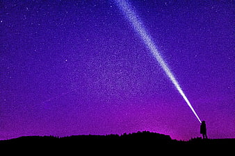 Silhouette of Person Shining Flashlight into Purple Starry Night Sky