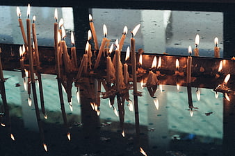 Lit prayer candles with reflections in a church window
