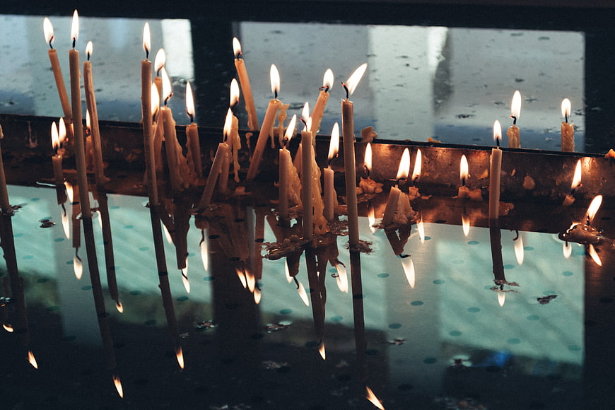 Lit prayer candles with reflections in a church window