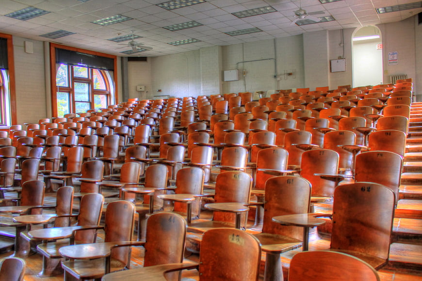 Empty wooden lecture hall with rows of student desks