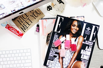 Flat lay of Elle magazine, nail polish, and computer workspace