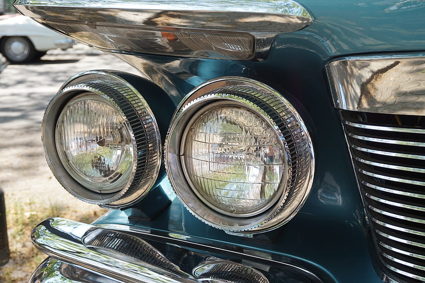 Close-up of vintage teal car headlights and chrome grille
