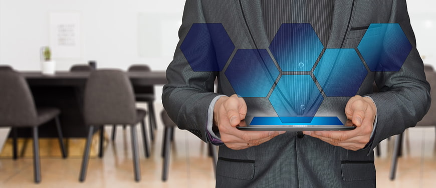 Businessman holding tablet with blue hexagon hologram projection