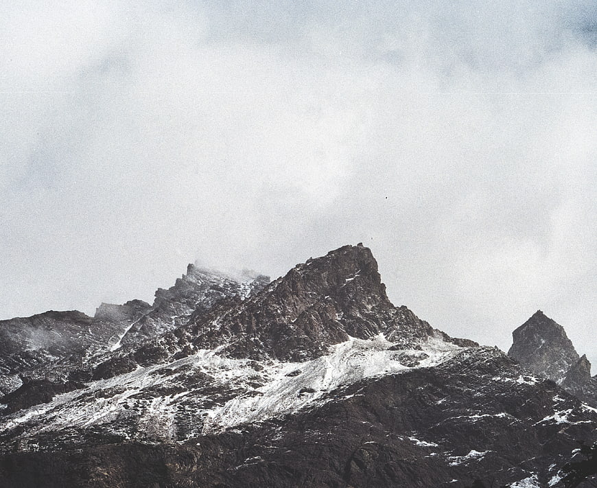 Dramatic Snow-Capped Mountain Peak Under Cloudy Sky