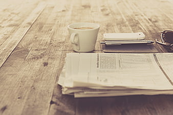 Vintage coffee cup, newspaper, and smartphone on rustic wooden table