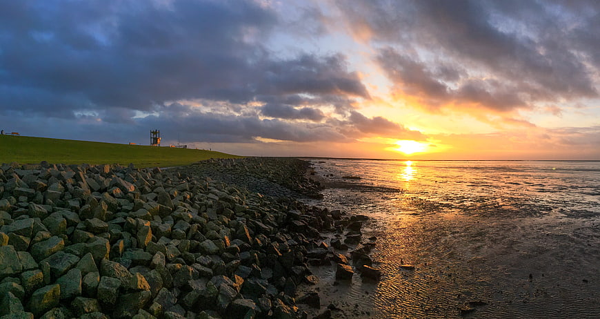 Dramatic sunset over rocky dike and calm sea