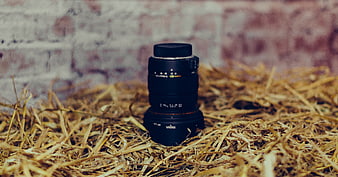 Camera lens on straw with brick background