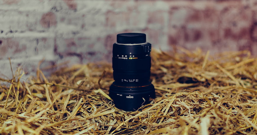 Camera lens on straw with brick background