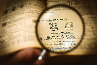 Magnifying glass inspecting vintage philatelic catalog text