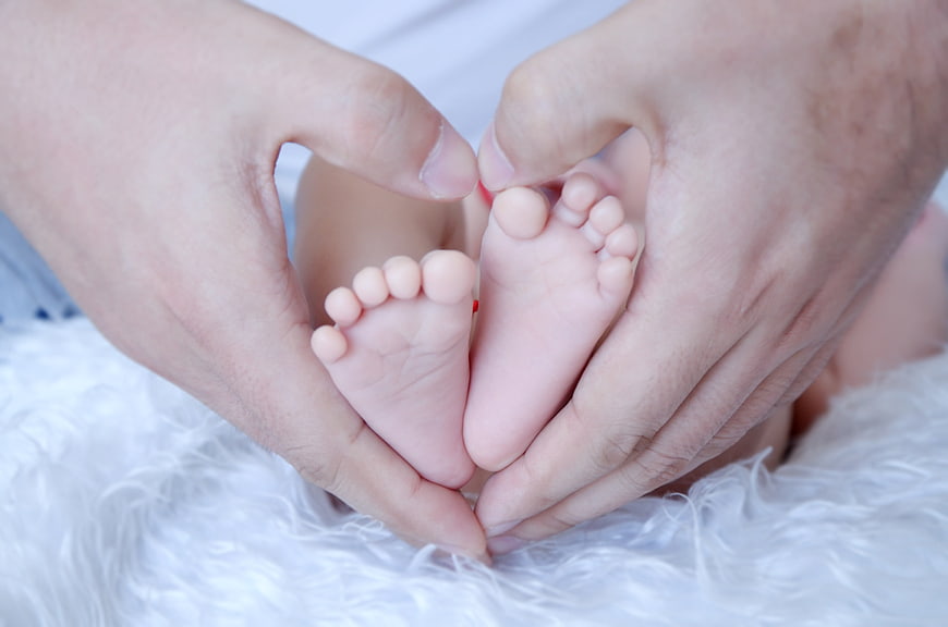 Father's Hands Forming Heart Shape Around Baby's Feet