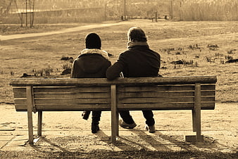 Couple sitting on park bench in sepia tone