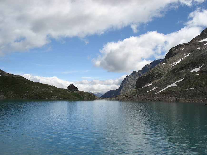 Serene Alpine Lake with Mountain Hut and Snowy Peaks
