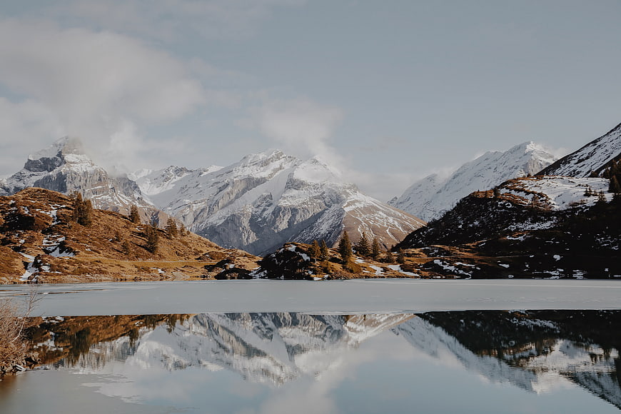 Snowy mountain peaks reflected in a calm alpine lake