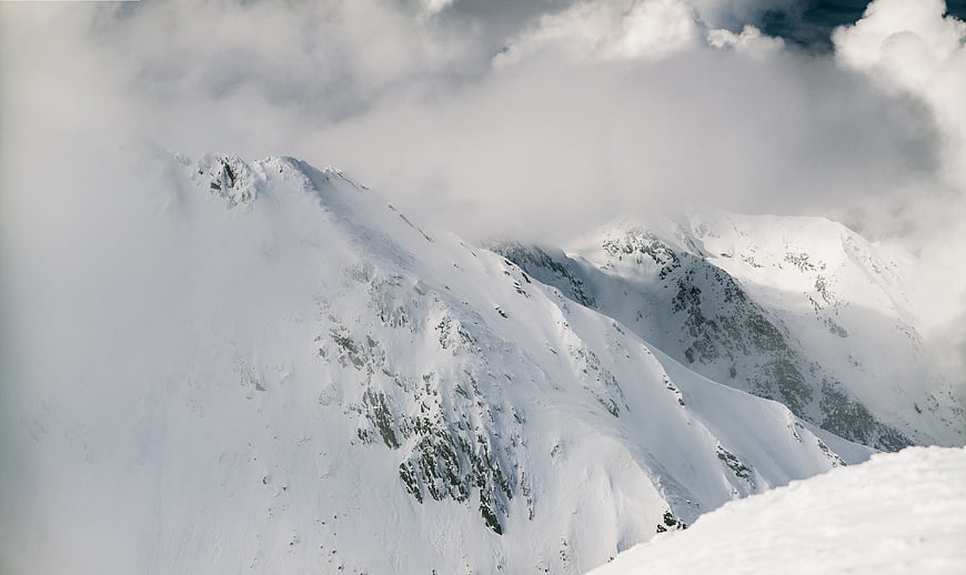 Snowy Mountain Peaks Through Clouds