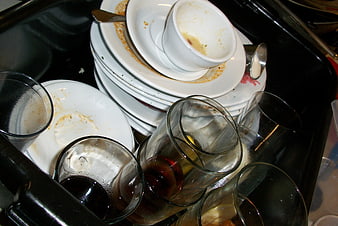 Dirty dishes and glasses piled in a black kitchen sink