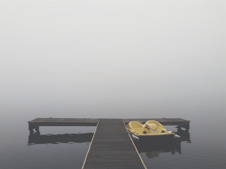 Yellow Pedal Boat on Wooden Dock in Foggy Lake