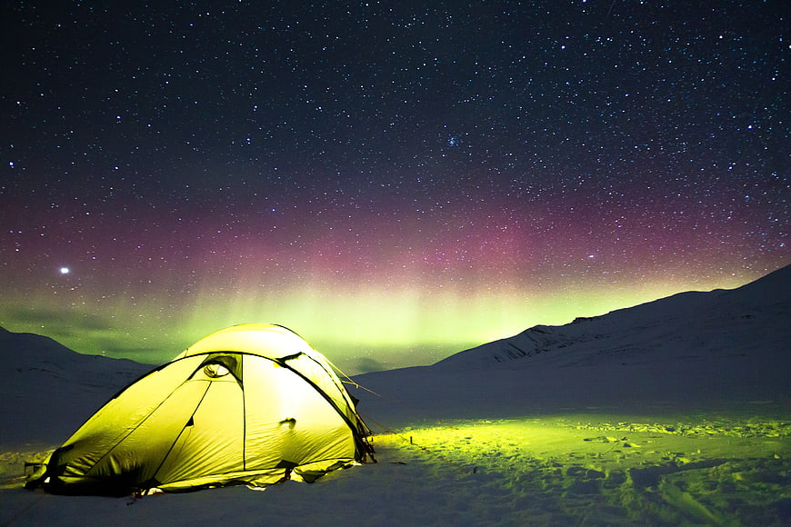 Illuminated Camping Tent Under Northern Lights and Starry Sky