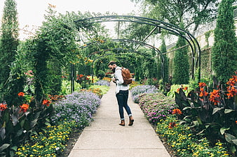 Man with backpack walking through lush garden path