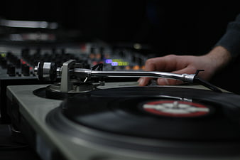 DJ Hand on Vinyl Record Turntable in Dark Club