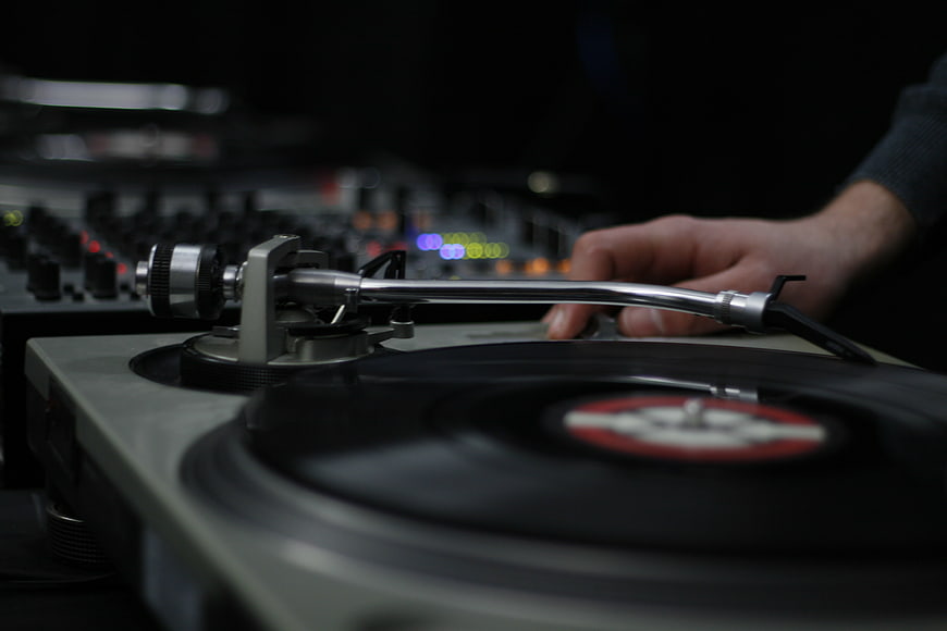 DJ Hand on Vinyl Record Turntable in Dark Club