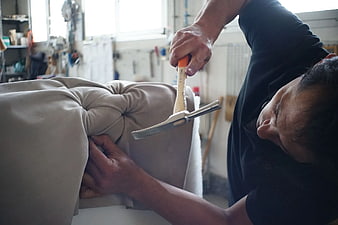 Upholsterer hammering tufted sofa in workshop